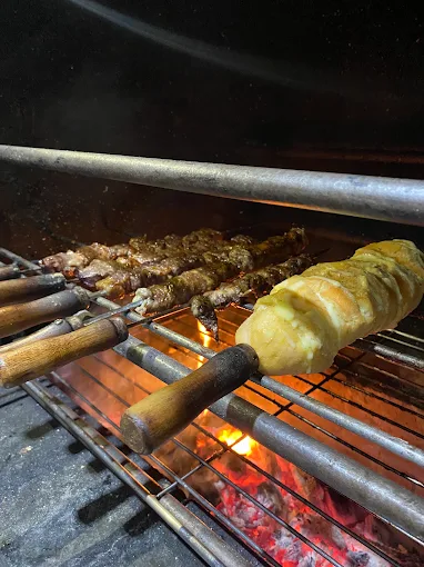 Espetos de carne e pão de alho assando na brasa da churrasqueira do Éder Espetos