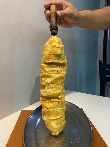 Pão de alho artesanal no espeto, dourado e coberto com creme de alho